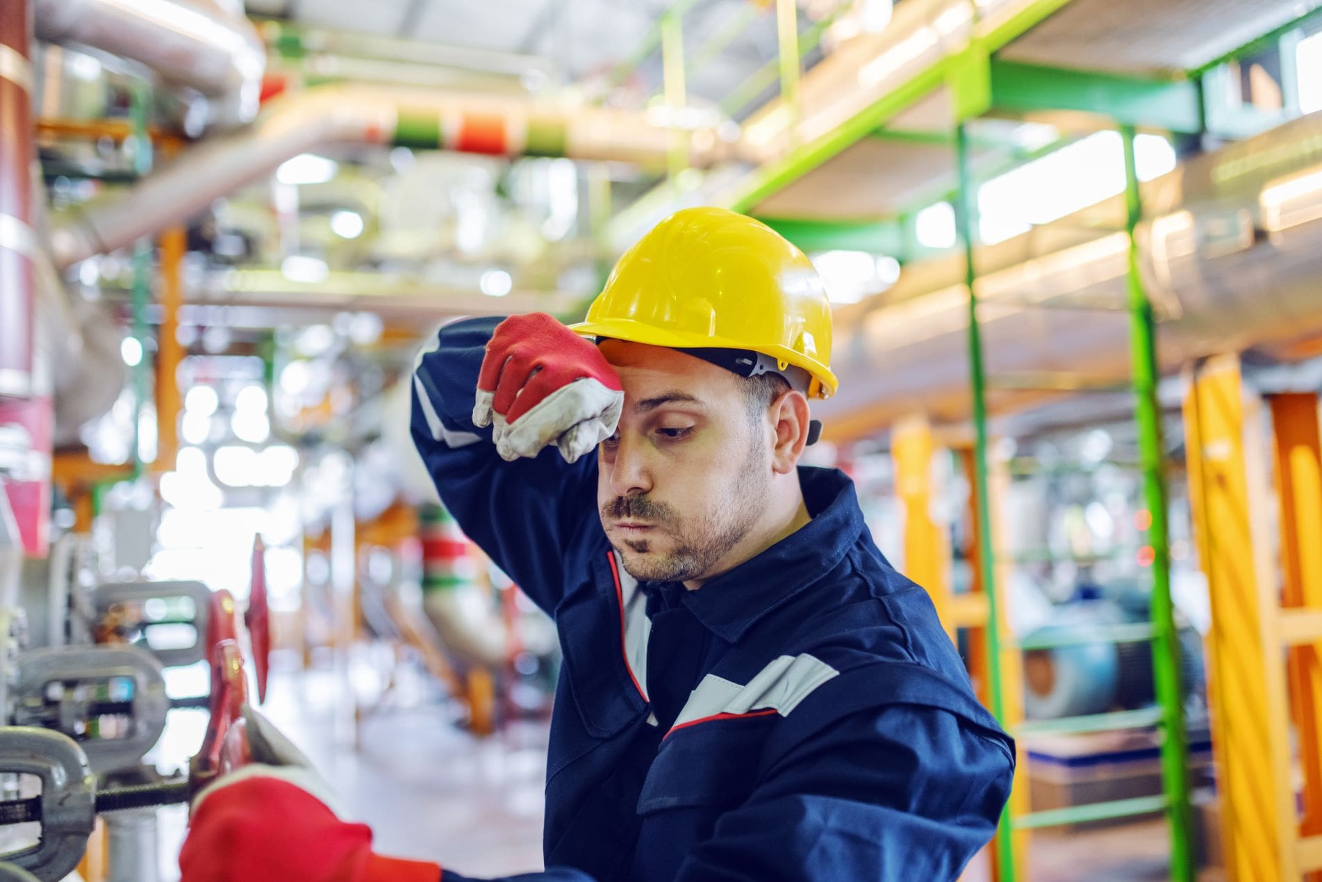 Worker In Factory Wiping Sweat From Brow