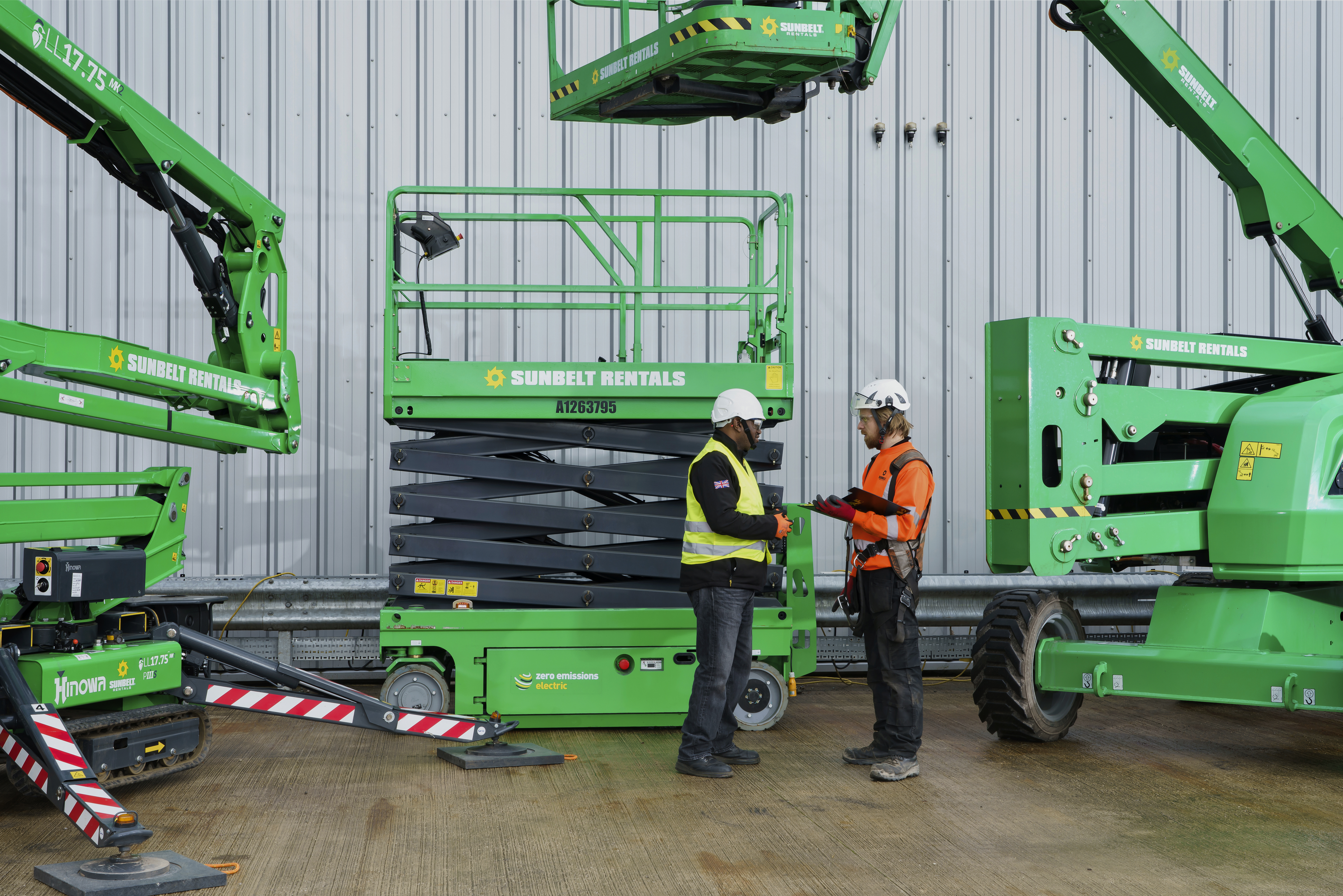 two technicians in front of an electric scissor lift