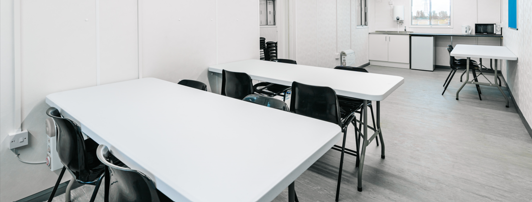 inside of a site canteen with white tables and black chairs
